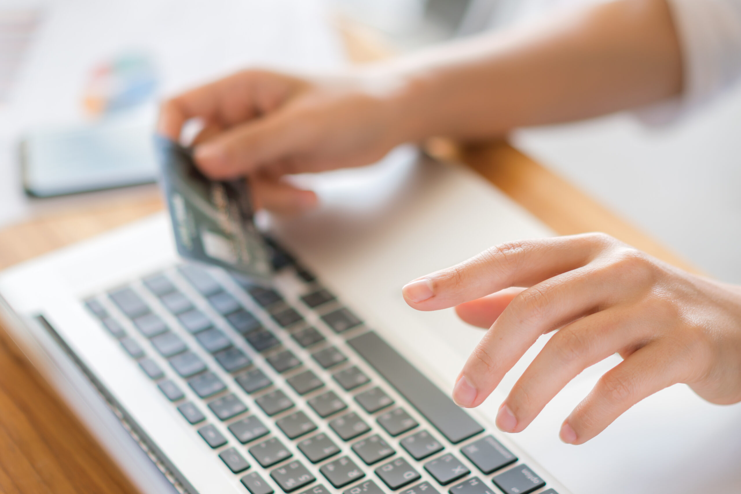 Hands holding a credit card and using laptop computer for online